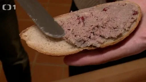 Rozmazání zvěřinové paštiky na chleba nožem.
