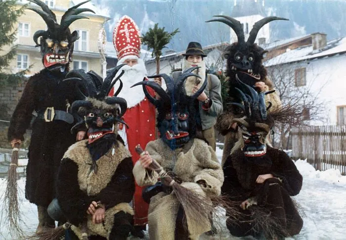 Skupina lidí v kostýmech čerta s rohy na sněhu.