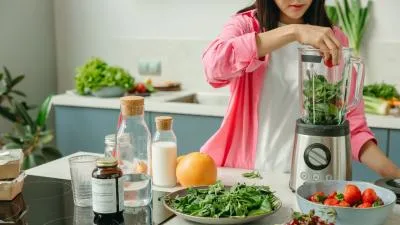 Žena připravuje smoothie se špenátem v kuchyni