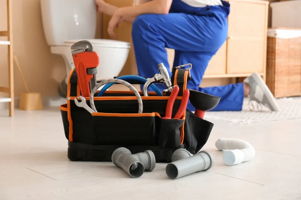 Profesionální nářadí instalatéra na podlaze v koupelně.
