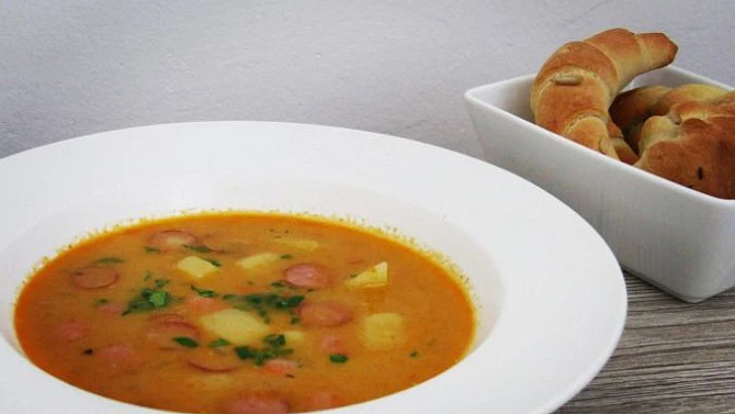 Hot Czech frankfurter soup with sausage slices, potato chunks and fresh herbs.