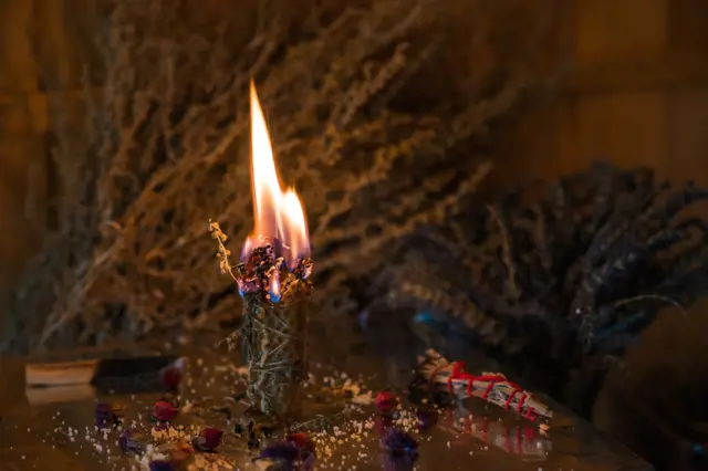 Spalující svíčka s bylinami pro odstraňování negativní energie v domě.