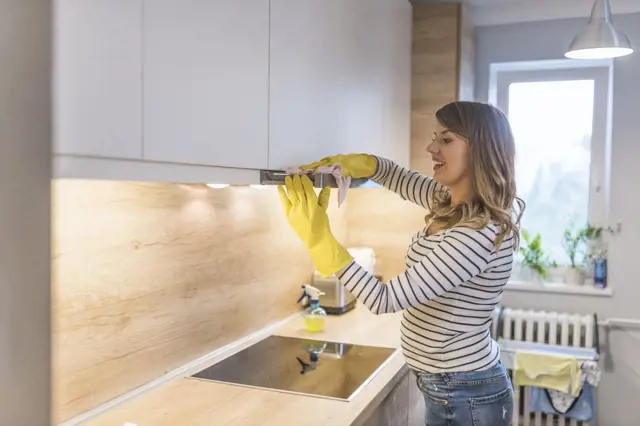 Žena čistí digestořový filtr pod kuchyňskou skříni