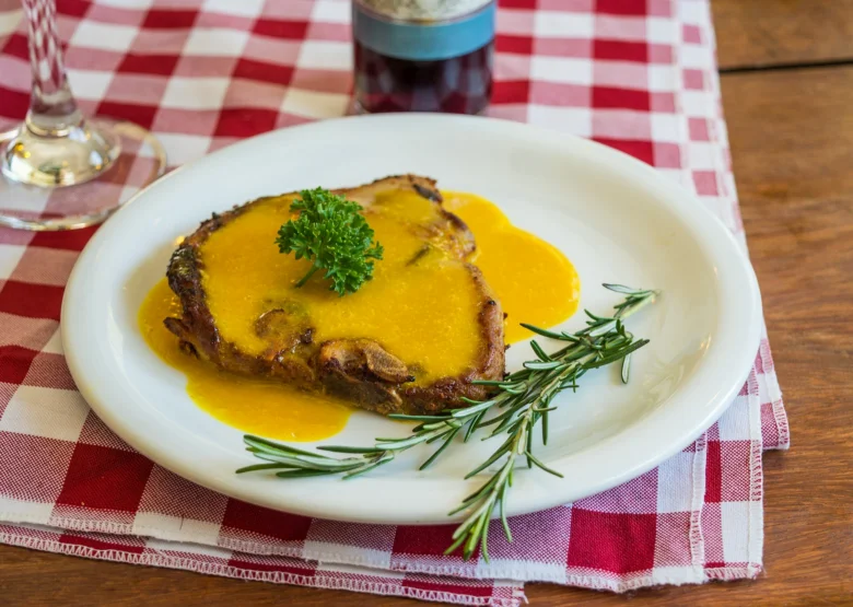 Hot steak with rich tomato sauce, garnished with herbs.