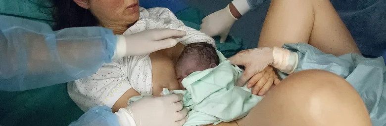 Matka drží novorozence po porodu v nemocničním prostředí.
