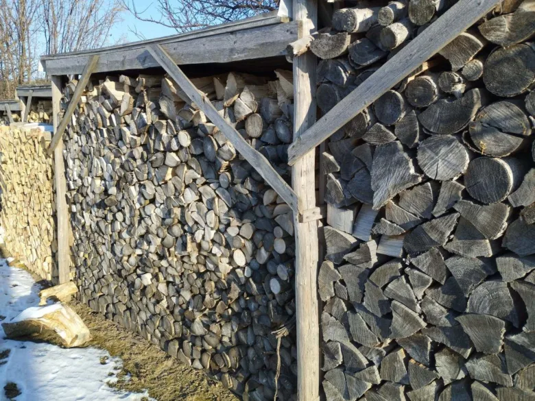 Nápadně uspořaný dřevník pod střešní konstrukcí.