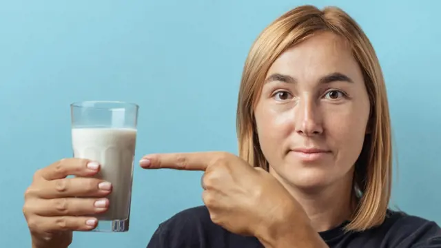 Žena ukazuje na sklenici mléka.
