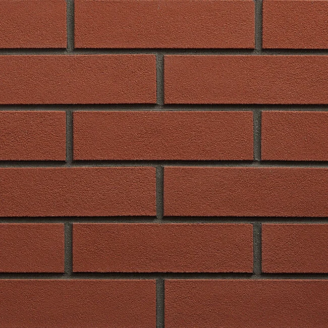 Červená cihlová zeď s viditelnými spárkami.