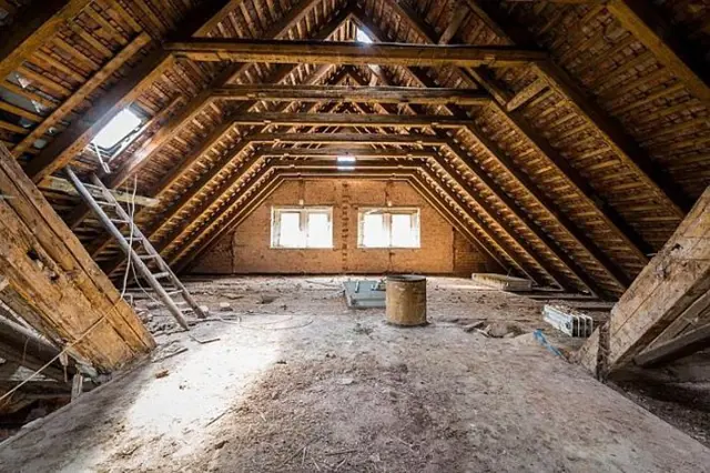 Nezhotovený podkroví s dřevěnými trámy před realizací.