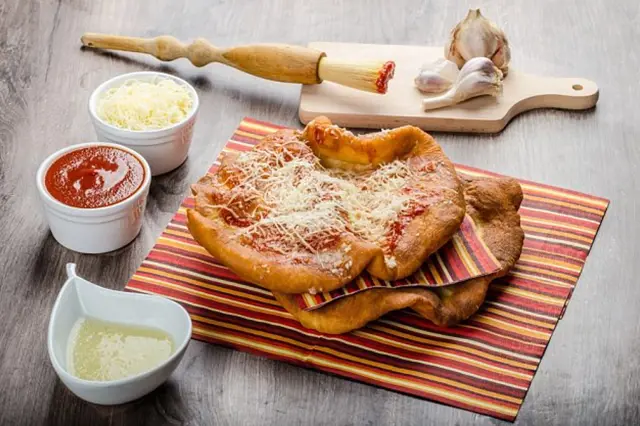 Slovenský langoš s česnekem a omáčkami na stolu