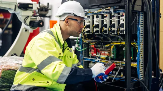 Průmyslový elektrikář měří napětí v rozvaděči na továrně.