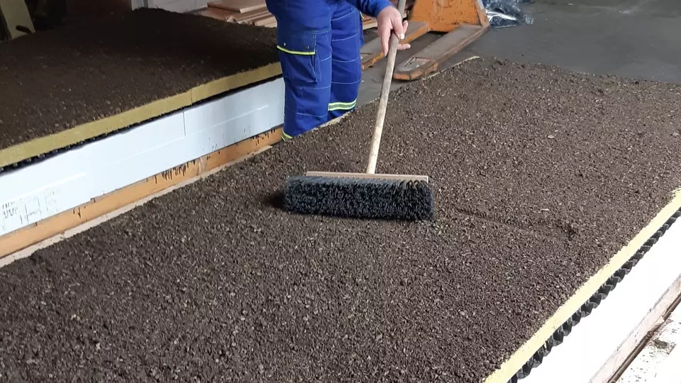 Pracovník čistí podlahu velkým kartáčem v továrně.