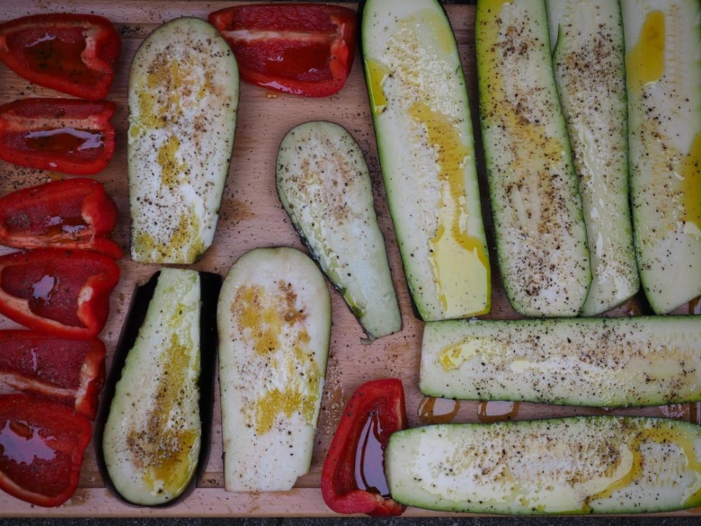 Našeřízené plátky cukety a baklažánu na dřevěném prkénku.