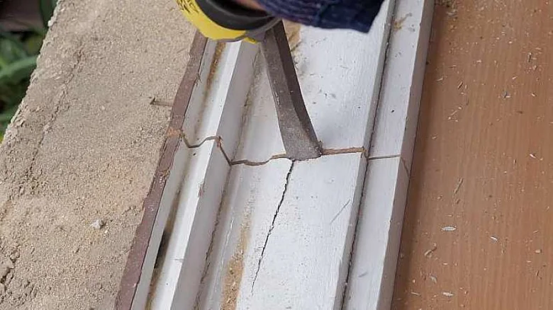 Nástroj pro demontáž starého dřevěného okenního rámu při renovaci.
