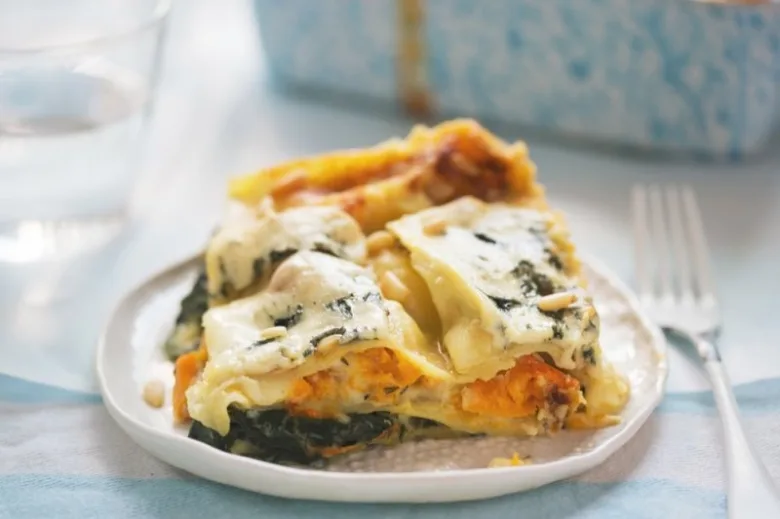 Kousek dýňové lasagne se špenátem na talíři.