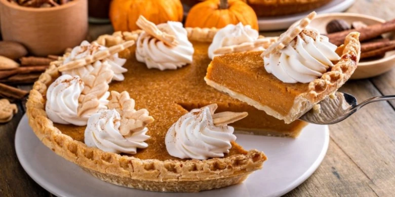 Pumpkin pie s kouskem na lžíci, ozdobená smetanou.
