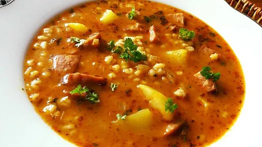 Hot Czech vegetable paprika soup in a white bowl.