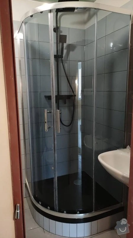 Nová sprchová kabinka v rekonstruované garsonce s dlažbou.