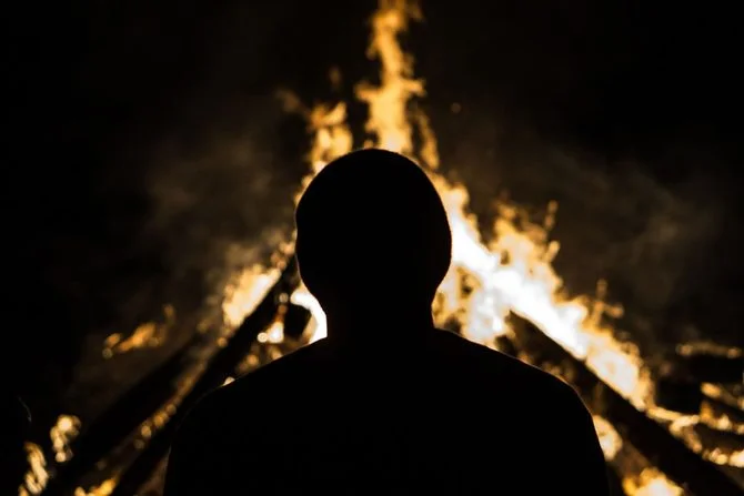 Silhouette of person watching bonfire