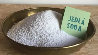 Hromada jedlé sody v kovové misce vedle zelené karty.