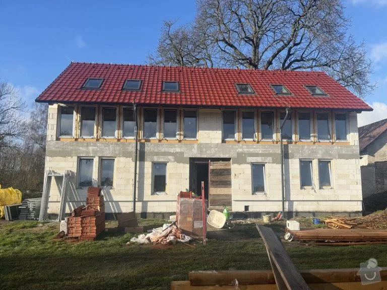 Montovaný dům v stavbě s červenou střechou na trávníku.