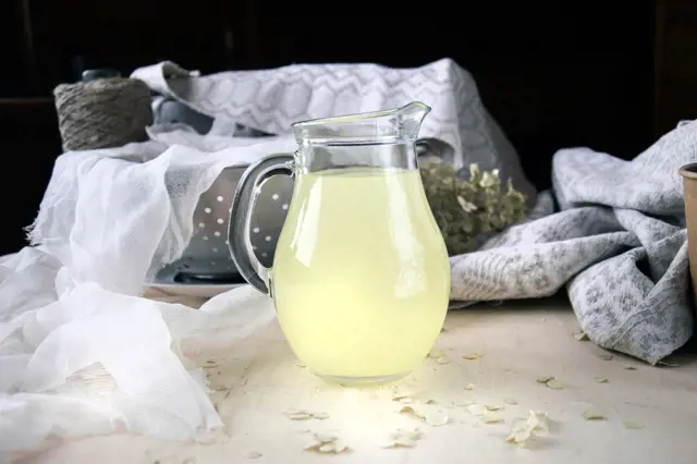 Sklenička s citronovým nápojem na dřevěném povrchu.