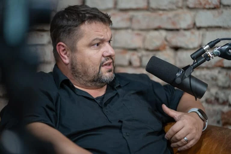 Muž mluví do mikrofonu při rozhovoru nebo podcastu.