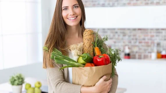 Žena drží tašku s čerstvými zeleninovými produkty.