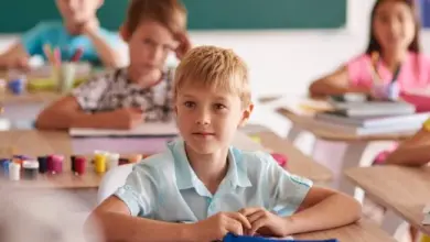 Chlapec sedí v třídě u stolu s učebnicemi.