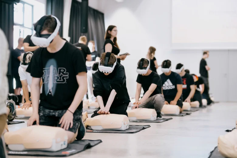 Lidé v VR brýlách praktikují masáž hrudníku na simulánech.