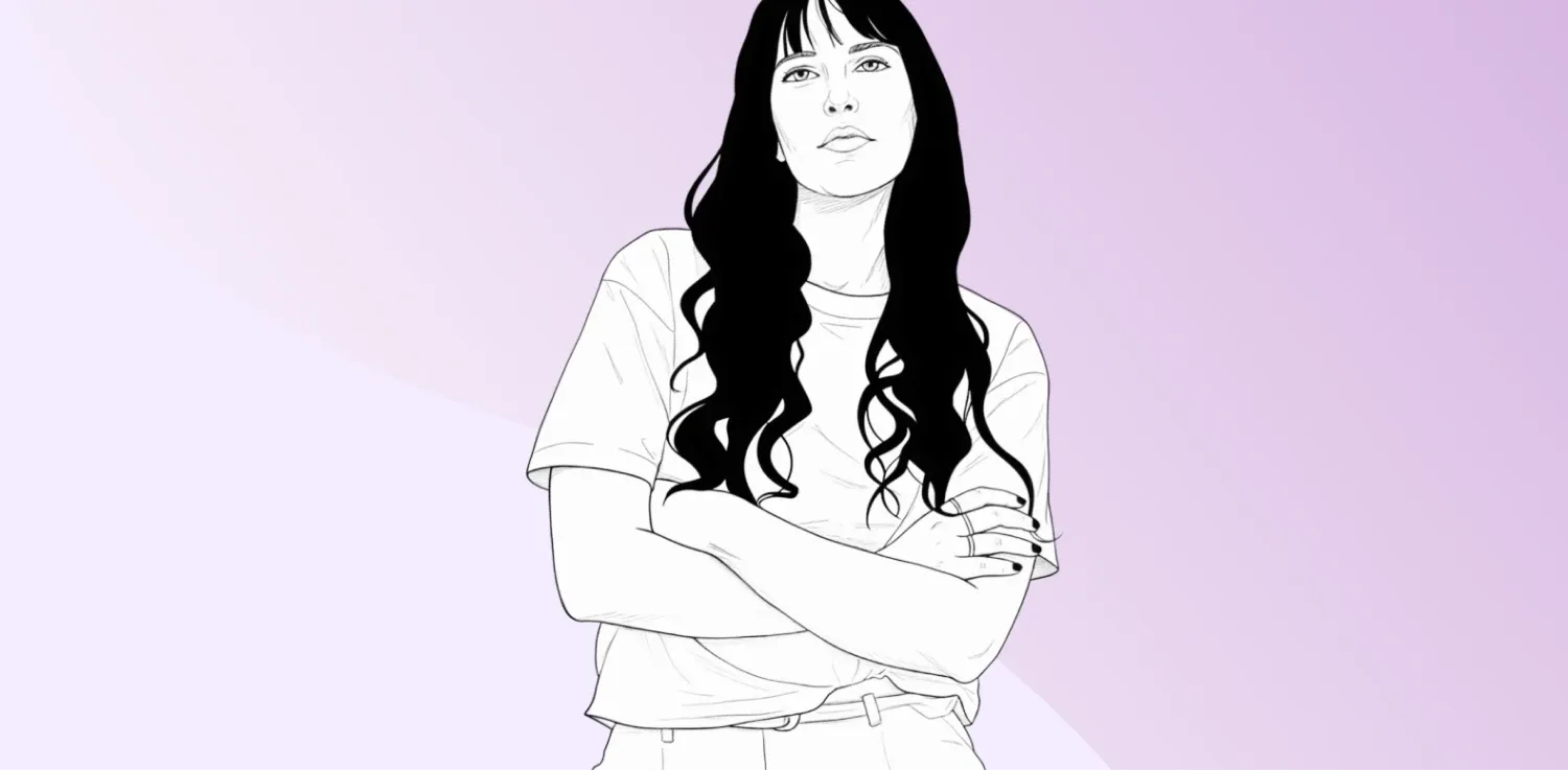 Žena s dlouhými vlasy v křížených pažích hledí přímo.