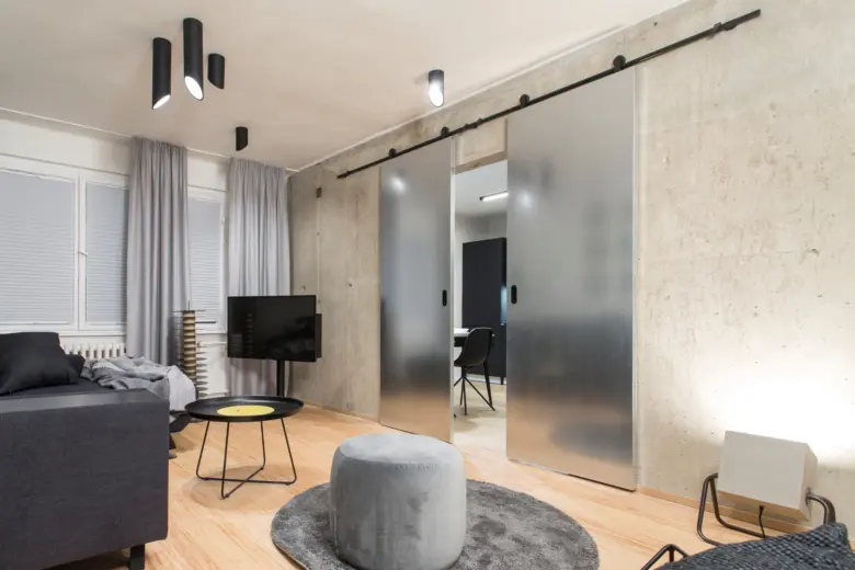 Posuvné dveře na stěnu v moderním interiéru s betonovou zdí.