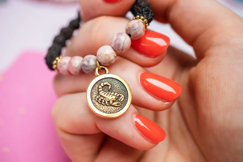 Zlatý amulet s kancem na náramku v ruce.