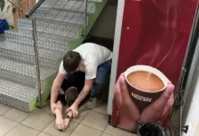 Muž poskytuje první pomoc člověku na schodech u kávomatova.